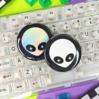 Two alien face buttons on a transparent keyboard with colorful keys.