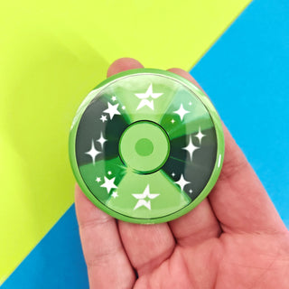 Green cd button with star patterns held in a hand against a colorful background