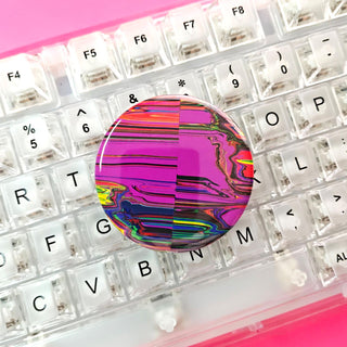 Colorful round object on a transparent keyboard with a pink background