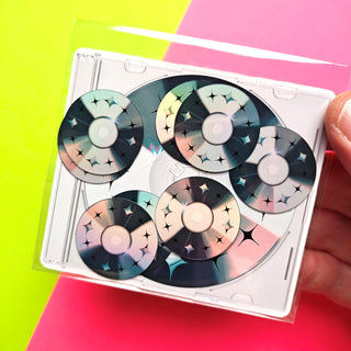 Set of decorative CDs in a clear plastic case held against a colorful background