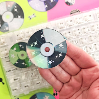 Hand holding a decorative CD with star patterns on a keyboard background