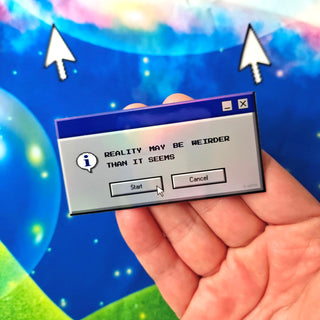 Hand holding a computer dialog box with text 'Reality may be weirder than it seems' against a colorful, abstract background.