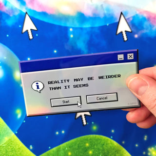Hand holding a computer dialog box with text 'Reality may be weirder than it seems' against a colorful, cartoon-like background.