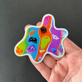 Acid Meltdown Holographic Sticker by AIPYR laying on a human hand over a black background.