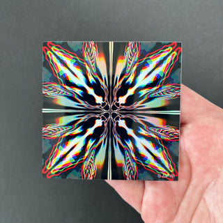 Chromatic Glitch Holographic Sticker by AIPYR laying on a human hand over a black background.