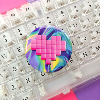 Pixel heart design on a colorful round object on a keyboard