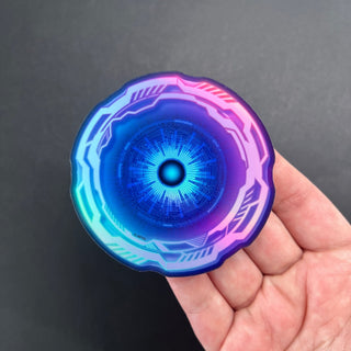 Cyber Eye Holographic Sticker by AIPYR laying on a human hand over a black background.