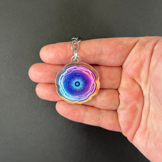 Mini Cyber Eye Keychain by AIPYR laying a human hand over a black background.