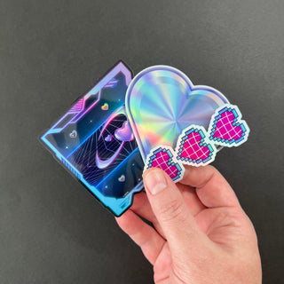 Cyber Hearts Holographic Sticker Pack by AIPYR laying on a human hand over a black background.