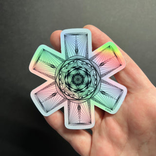 Ecliptic Gateway Holographic Sticker by AIPYR laying on a human hand over a black background. 