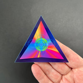 Ethereal Triangle Holographic Sticker by AIPYR laying on a human hand over a black background. 