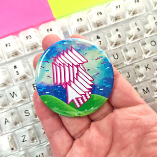 Colorful button held by a hand with a keyboard in the background