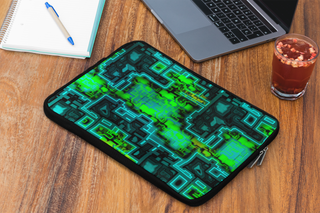 Laptop case with green circuit board design on a wooden desk