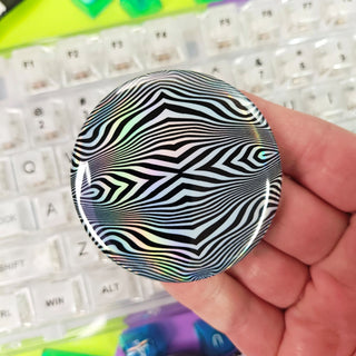 Hand holding a black and white patterned object over a keyboard