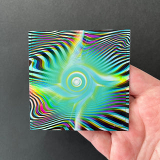 Hypnotic Void Holographic Sticker by AIPYR laying flat on a human hand over a black background.