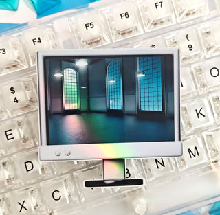 Teal keyboard keys scattered on a white keyboard with a small screen displaying an image of a room.
