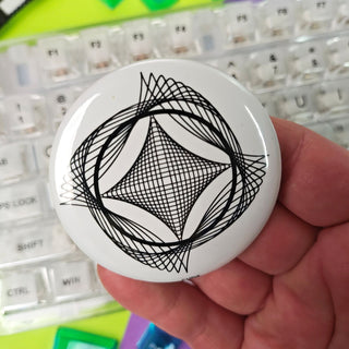 Hand holding a white button with black geometric design against a colorful keyboard background
