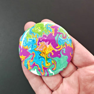 Colorful swirl design on a round object held in a hand against a dark background