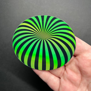 Neon Green Orb Holographic Sticker by AIPYR laying on a human hand over a black background.