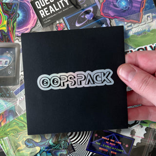 Mystery Oops Sticker Pack by AIPYR in a black envelope held by a human hand over a pile of oops stickers.