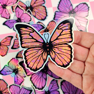 Butterfly-shaped sticker held by a hand with more butterfly stickers in the background