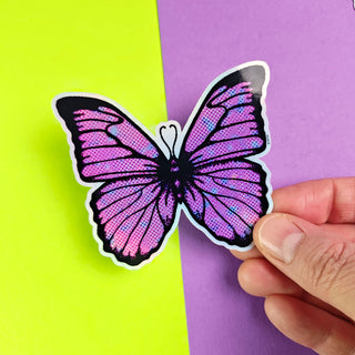 Butterfly-shaped sticker held by a hand on a purple and green background