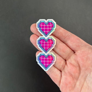 Pixelated Hearts Holographic Sticker by AIPYR laying on a human hand over a black background.