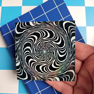 Black and white spiral design on a card held over a blue and white checkered background