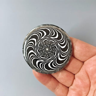 Black and white striped object held in a hand against a gray background