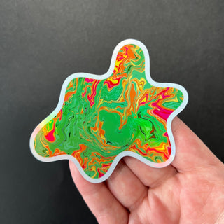 Slime Green Blob Holographic Sticker by AIPYR laying on a human hand over a black background.