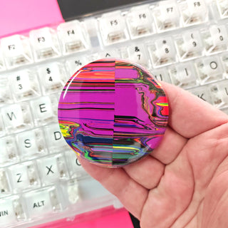 Hand holding a colorful, iridescent object in front of a keyboard