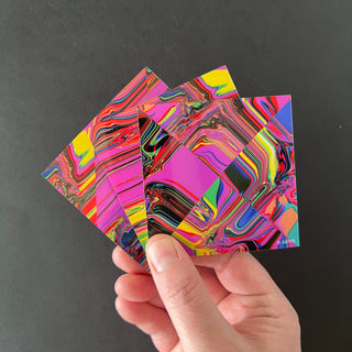 Trippy Glitch Holographic Sticker Pack by AIPYR held by a human hand over a black background.