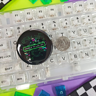Clear keyboard with colorful keys and a round black object on a checkered and multicolored surface.