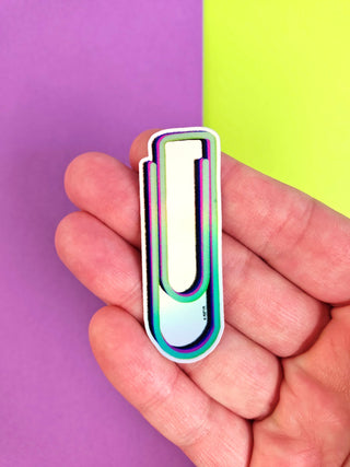 Colorful paper clip-shaped object held in a hand against a purple and green background