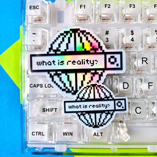 Keyboard with pixel art design of a question mark and text 'what is reality?' on a blue and green background.