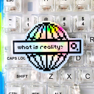 Keyboard with a colorful 'what is reality?' sticker