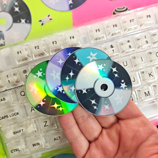 Three colorful CDs held in front of a keyboard