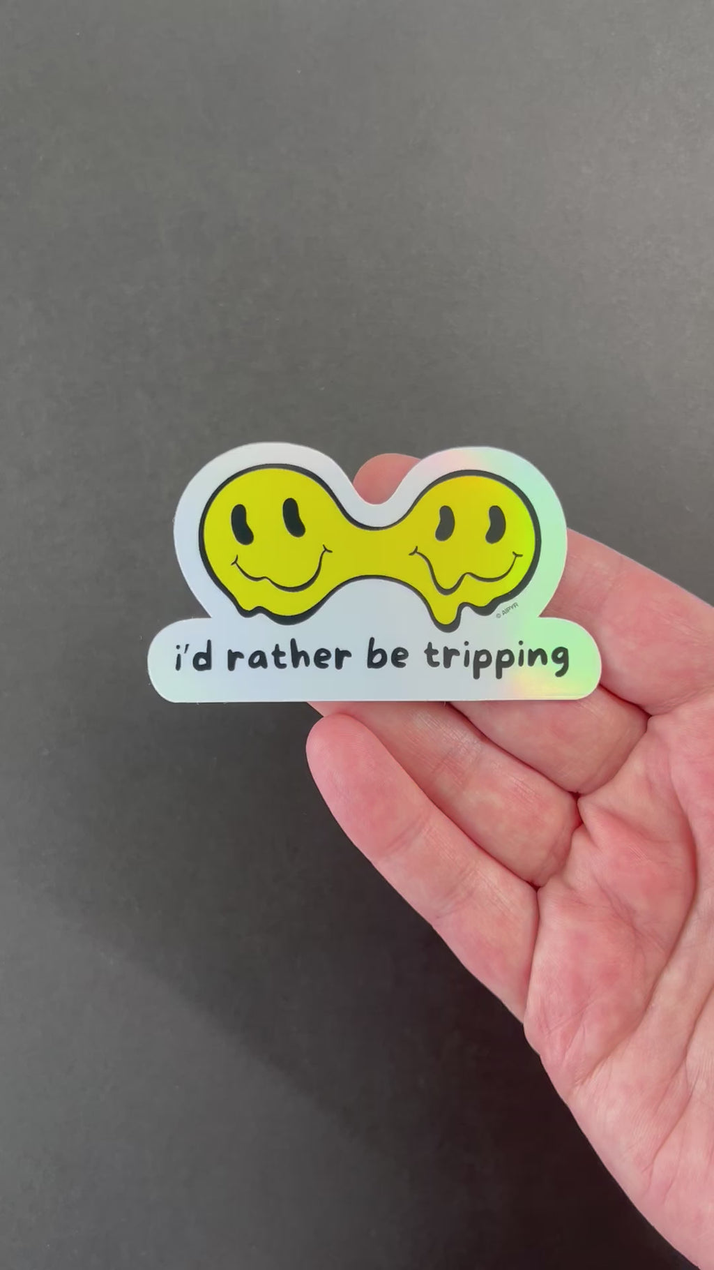 Video of the I'd Rather Be Tripping Holographic Sticker by AIPYR over a black background.