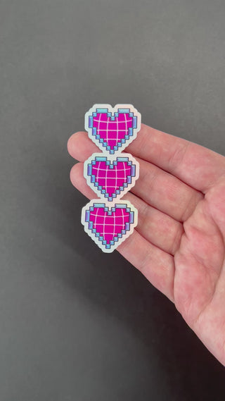 Video of the Pixelated Hearts Holographic Sticker by AIPYR over a black background.